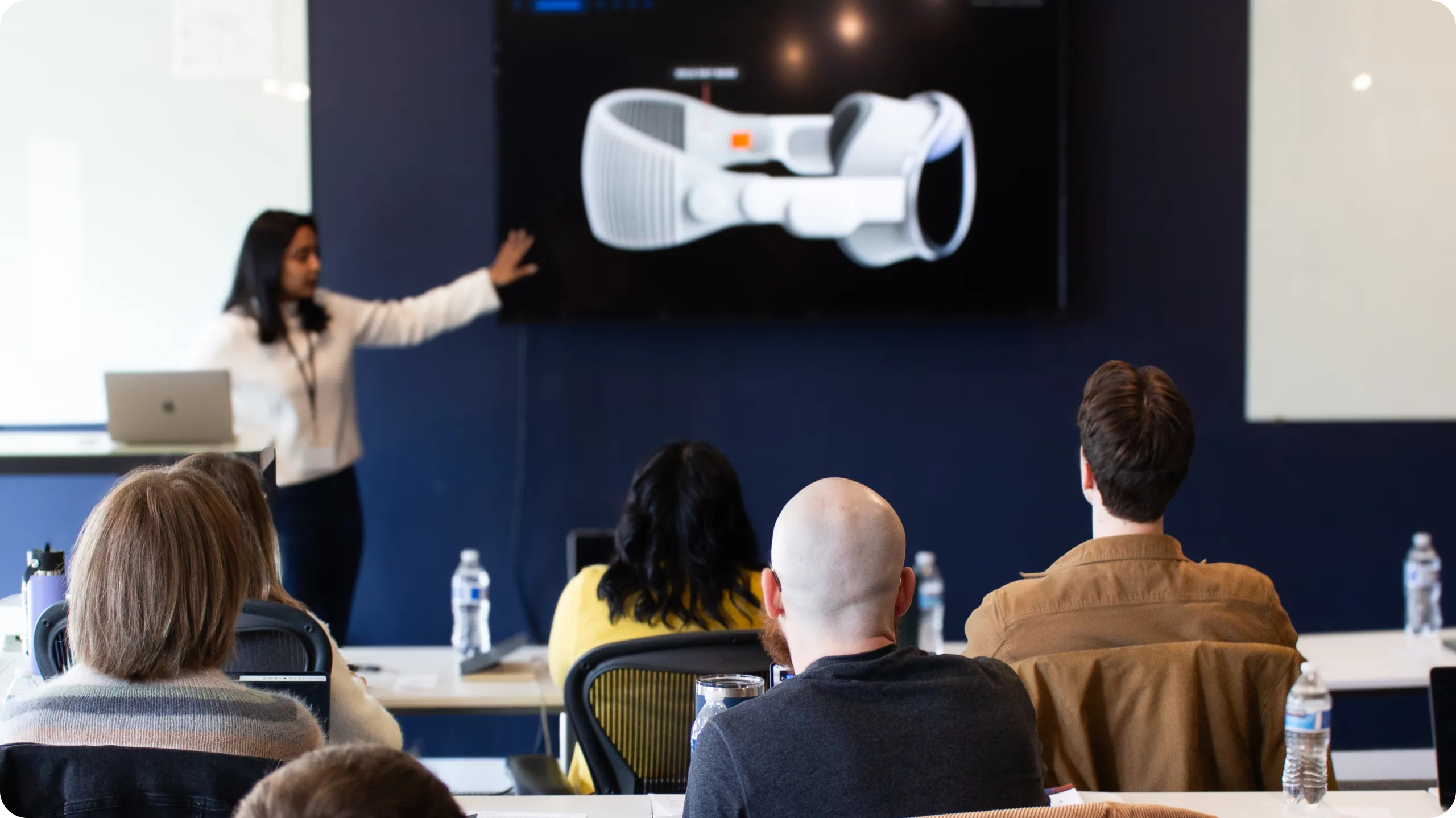 Woman giving a presentation with an Apple Vision Pro on a television screen.