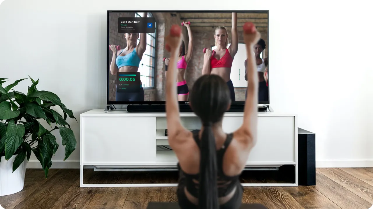 Woman following a workout class on her TV.