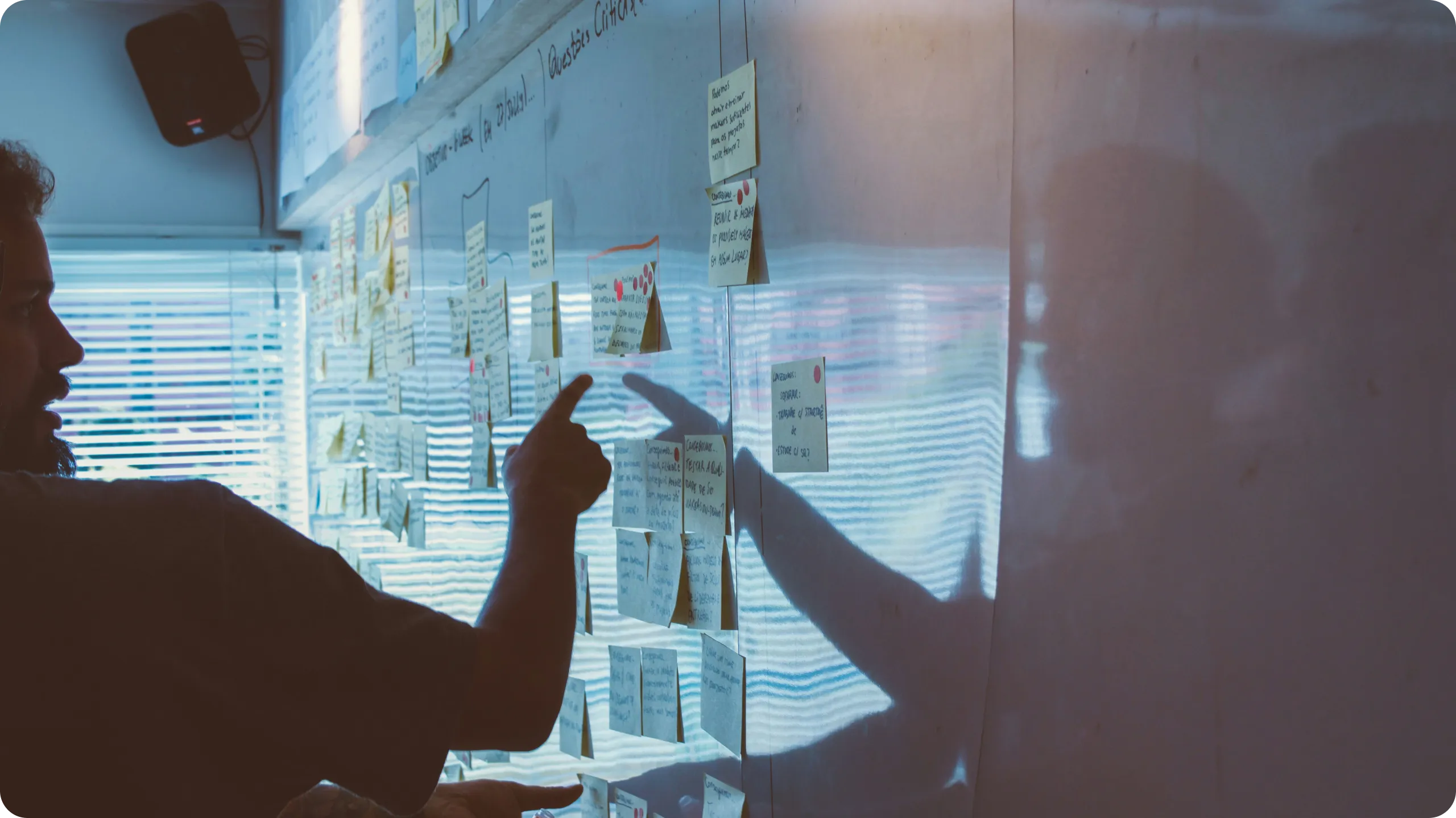 Two people collaborating with sticky notes on a whiteboard.