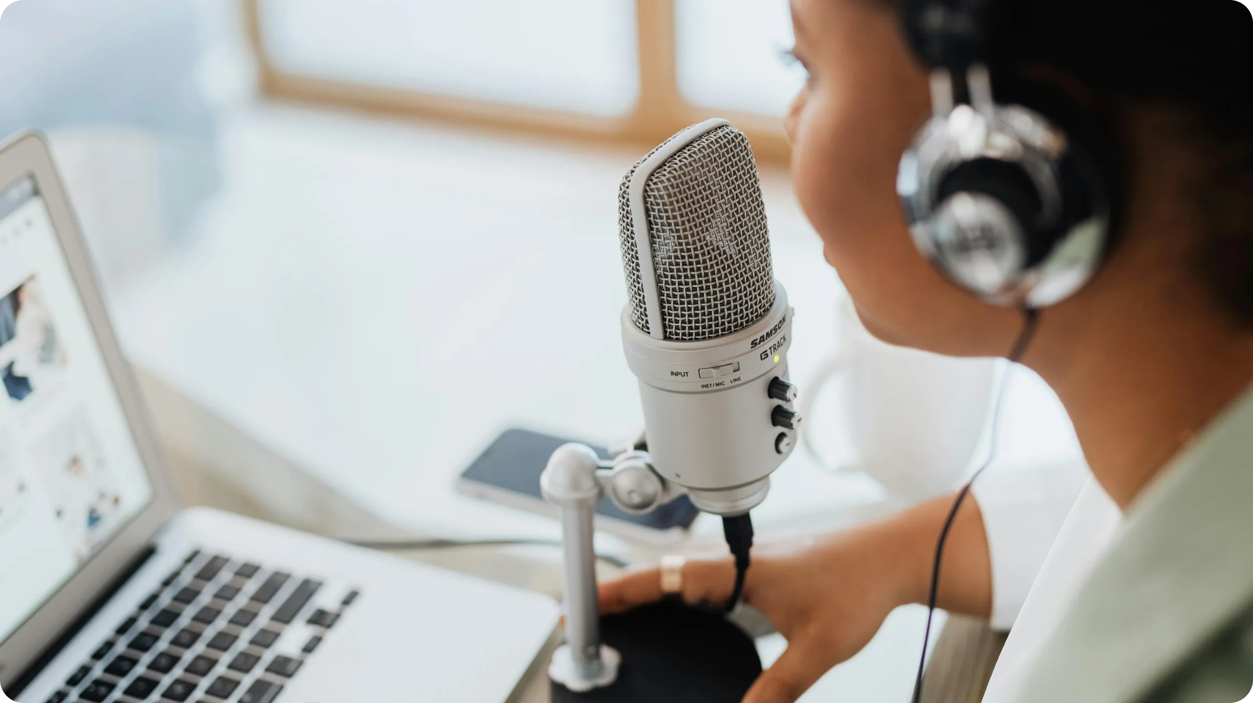 Podcaster at a computer speaking into a microphone.