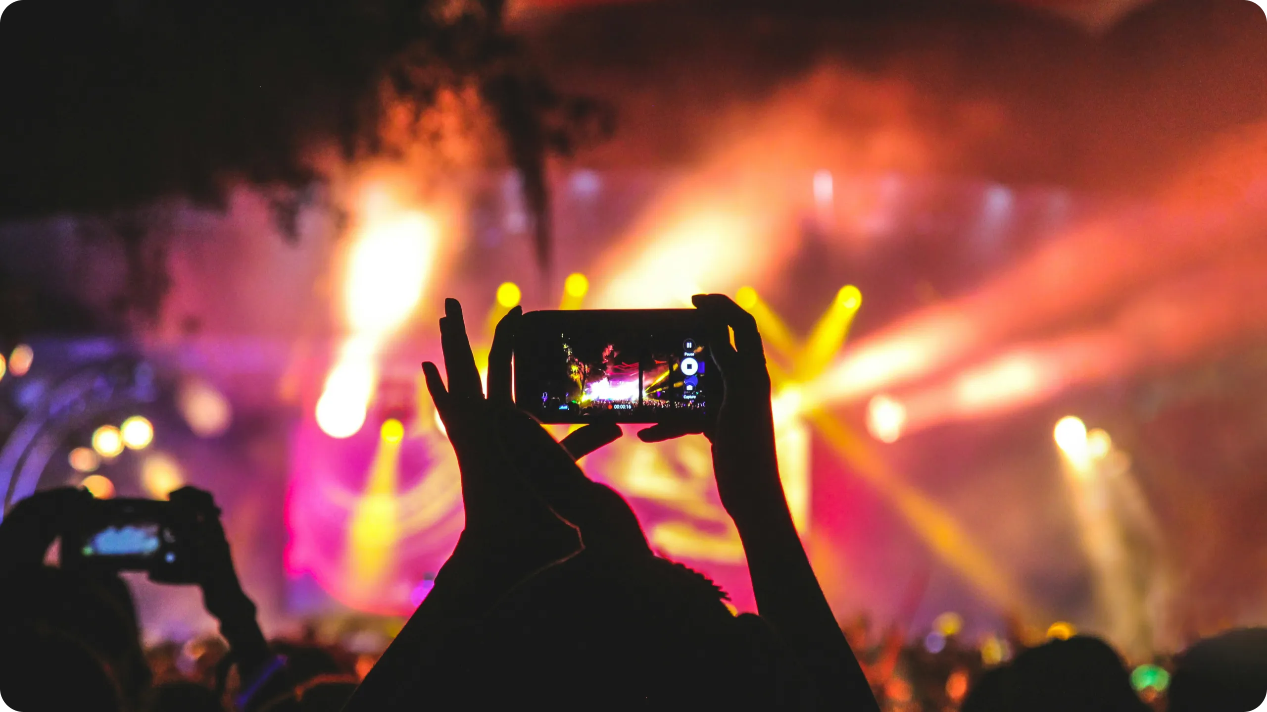 Person at a concert recording a video on a mobile phone.
